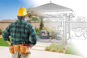 26254140 contractor standing looking at patio pergola design drawing and photo combination